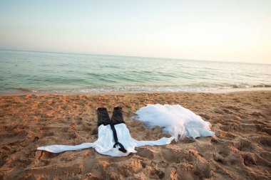 ıslak giysiler siyah pantolon ve beyaz gömlek kumlu sahildeki gelinlik yanında yalan