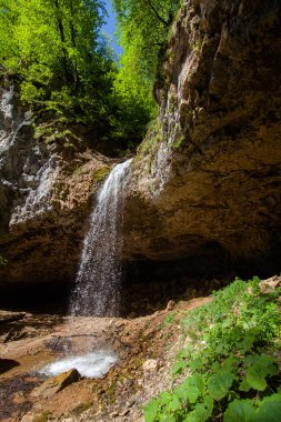 altında güneşli bir gün Whit gölet üzerinde asılı kayalar ile güzel yüksek düşen şelale