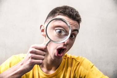 Komik bir yakışıklı çocuk a magnifying cam içinde arıyorum