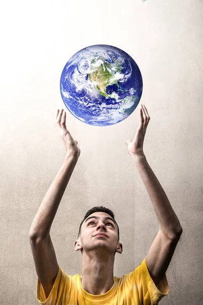 Niño estirando los brazos para agarrar el planeta Tierra — Foto de Stock