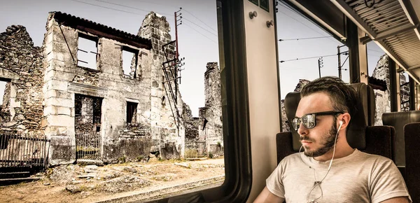 Νεαρός άνδρας που βλέπει την πόλη να καταστρέφεται μέσα από το παράθυρο του τρένου — Φωτογραφία Αρχείου