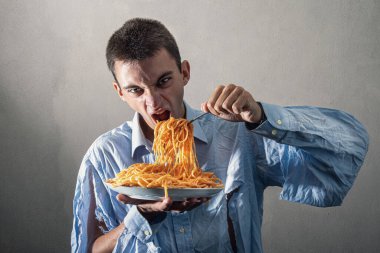 Domates soslu spagetti yiyen bir adam.