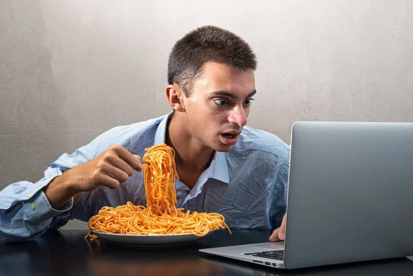 Man Som Äter Spaghetti Med Tomatsås Och Tittar Datorn — Stockfoto