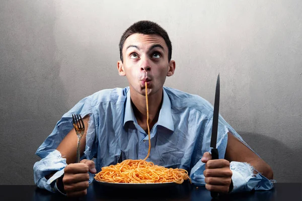 Domates soslu spagetti yiyen bir adam.