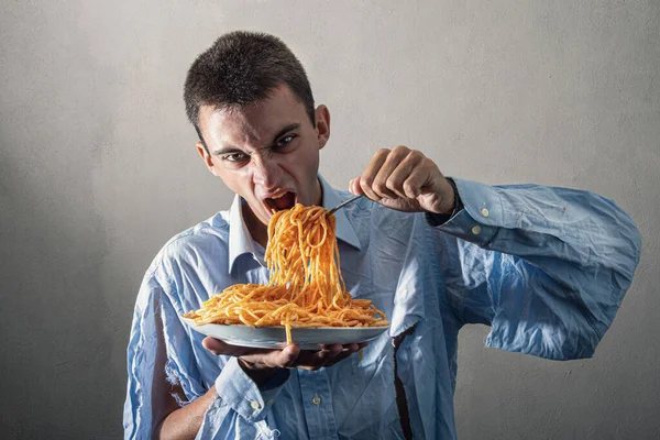 Domates soslu spagetti yiyen bir adam.