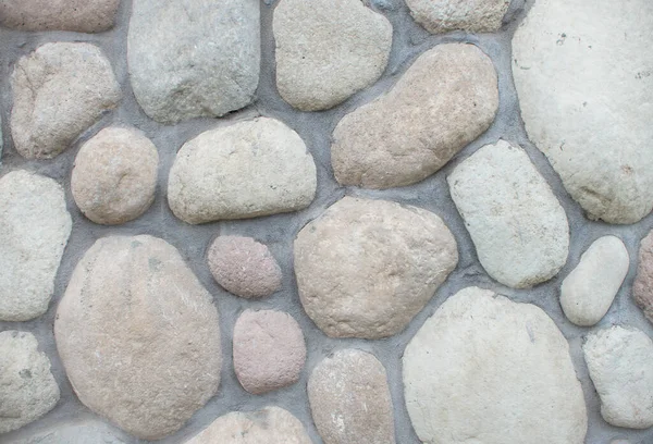 Wall round stone rock texture background. Big stones on the roadway.