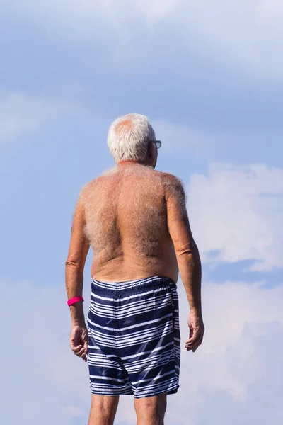 Hairy men back.Man with a very hairy back standing outside on a hot summer day.