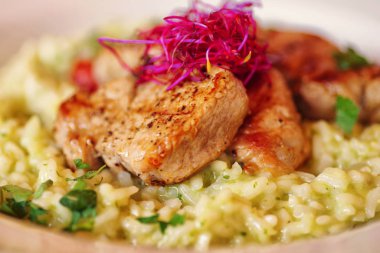 Pirinç lapası adet kızarmış et kabuk ve hafif derin plaka üzerinde taze otlar ile.