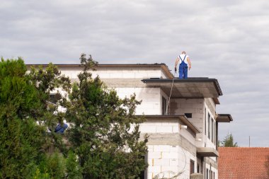 İnşaatçılar bir ev inşa. İşçi iş elbiseleri evde üstüne bir çatı yapmak.