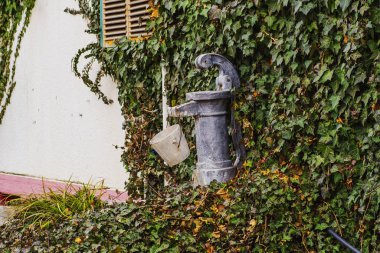 Gri bir vintage sokak dokunun su için bahçede anlamına gelir ve bir demir su kova üzerinde asılı.