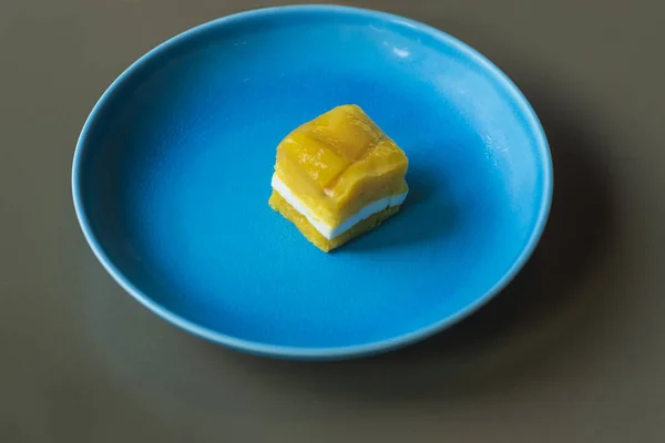 A small piece of yellow cake on a blue plate. Yellow dessert on a blue plat .Yellow dessert.