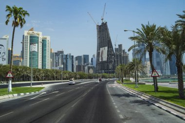 Doha, Katar - 4 Ağustos 2018: Doha modern şehir palmiye ağacı, arabalar, Doha Şehir mavi gökyüzünde üzerinde geniş caddeleri ile.