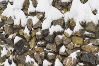 Winter landscape. A natural stone fence covered with snow. clipart
