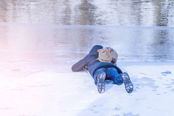 The man lies on ice in the winter,a man lies on the ice of the winter river and looks through the ice .