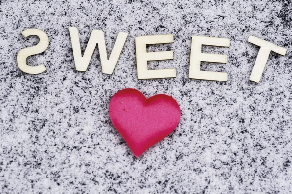 Heart drawn in the snow.Valentine\'s Day. Heart of pink in the snow with the letters sweet. Valentine\'s Day. Soft focus. Background. Close-up