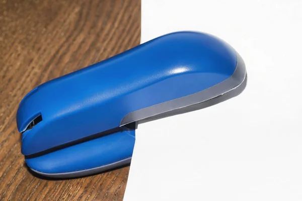 Office concept.Blue stapler on the table with a white sheet of paper.
