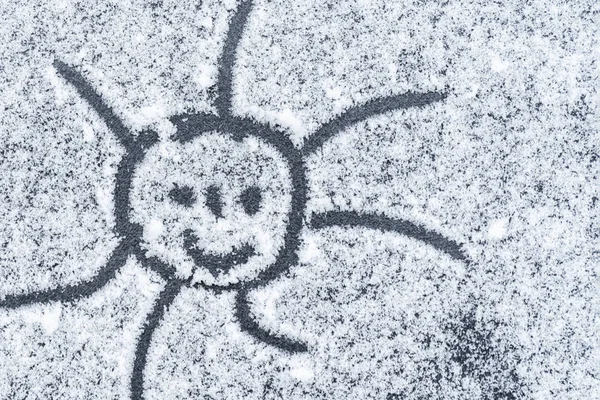 Smiling sun drawn on snow.Soft focus. Background. Close-up.Rozhitsy drawn on snow. Sun drawn in the snow.