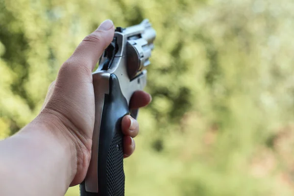 The concept of security. The gun in the hand of a woman. The girl is preparing to shoot.