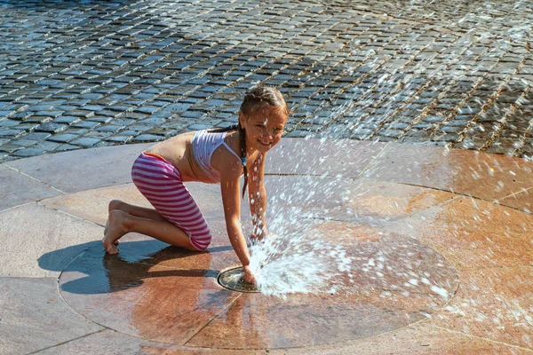 Meisje op een zonnige warme dag buiten spelen in een waterfontein. Meisje gelukkig in ondiepe schoon water op van stad fontein op warme heldere zomerdag. — Stockfoto
