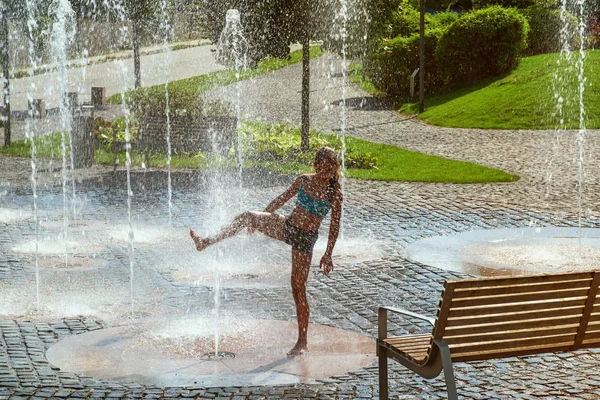 Meisje op een zonnige warme dag buiten spelen in een waterfontein. Meisje gelukkig in ondiepe schoon water op van stad fontein op warme heldere zomerdag. — Stockfoto