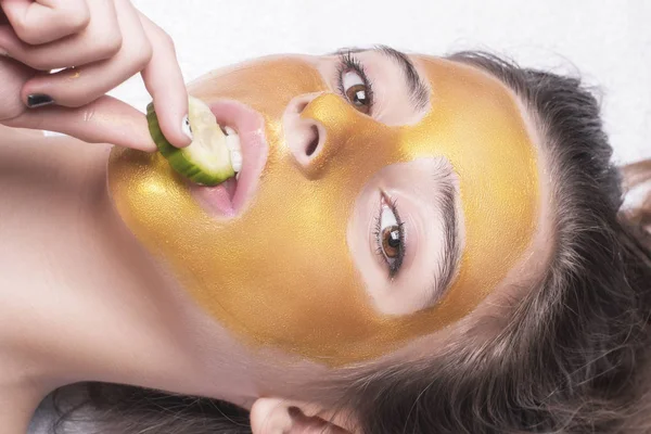 Gadis cantik dengan topeng kosmetik di wajah warna emas. Close-up. Ruang kosong. Wanita masker emas. Model indah menghapus kosmetik kulit wajah emas. Kecantikan kulit  . — Stok Foto