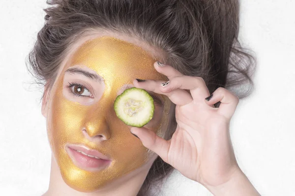 Mooi meisje met een cosmetische masker op het gezicht van gouden kleur. Close-up. Vrije ruimte. Vrouw gouden masker. Mooi model gouden gezichtshuid cosmetische verwijderen. Beauty huidverzorging . — Stockfoto