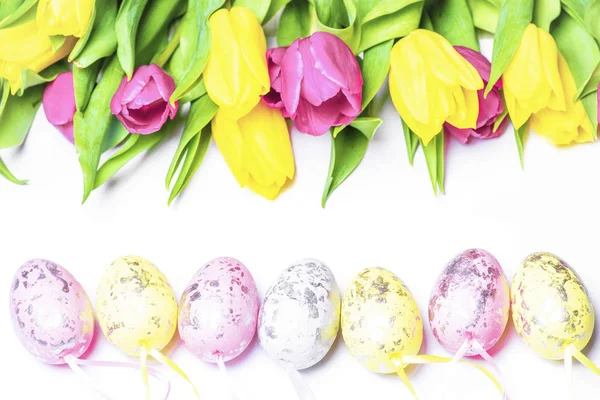 Tulipanes frescos sobre un fondo blanco con huevos de Pascua de colores. Feliz Pascua.Postal. Enfoques selectivos.Tarjeta de felicitación de Pascua.Copiar el espacio . —  Fotos de Stock