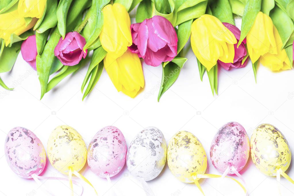 Fresh tulips on a white background with colored Easter eggs. Happy Easter.Postcard. Selective focus.Easter greeting card.Copy space.