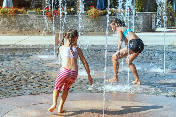 Bambini in una giornata di sole caldo giocare all'aperto in una fontana d'acqua. I bambini felicemente in acqua pulita poco profonda sulla fontana della città in calda giornata estiva luminosa . — Foto Stock