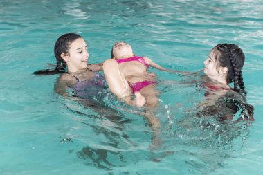 Üç kız Havuzda yüzmek. Threesisters Havuzu. Üç mutlu kız havuzda oyna. Güzel kızlar eğlenceli suda yüzmek ve sahip. Aktif tatil.