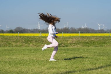 Çimlerin üzerinde zıplayan genç bir kız, sporun doğasında olan bir kız. Doğadaki kız akrobatik dublörler yapar.