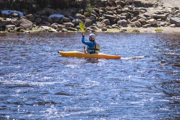 Człowiek na górskiej rzece jest zaangażowany w rafting. Dziewczynka spływy kajakiem w dół górskiej rzeki. dziewczyna w kajaku, widok z boku. — Zdjęcie stockowe