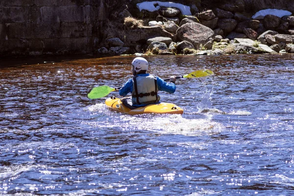 Człowiek na górskiej rzece jest zaangażowany w rafting. Dziewczynka spływy kajakiem w dół górskiej rzeki. dziewczyna w kajaku, widok z boku. — Zdjęcie stockowe