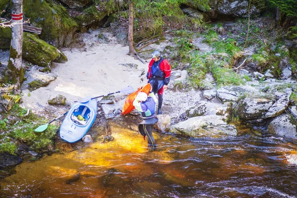 Man and woman on the kayak. A man and a woman on the bank of the river are resting pouring water from boats, carrying kayak to river.A view of the sport is kayaking.