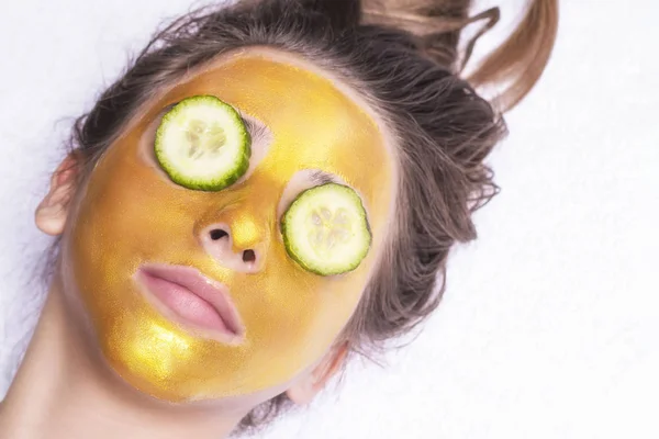 Mooi meisje met een cosmetische masker op het gezicht van gouden kleur. Close-up. Vrije ruimte. Vrouw gouden masker. Mooi model gouden gezichtshuid cosmetische verwijderen. Beauty huidverzorging . — Stockfoto