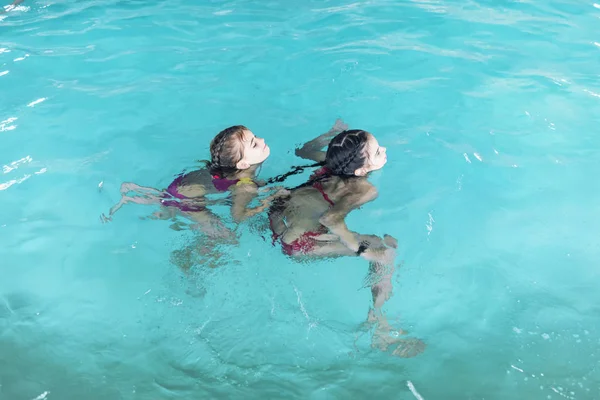 Deux filles nagent dans la piscine. Deux sœurs dans la piscine. Deux filles heureuses jouent dans la piscine.De belles filles nagent et s'amusent dans l'eau.Vacances actives . — Photo