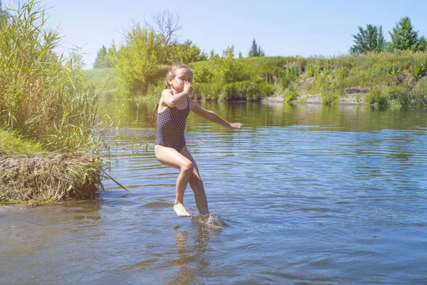 Μικρό κορίτσι που τρέχει μέσα στο νερό με έναν παφλασμό. στο πανί της χέρια. — Φωτογραφία Αρχείου