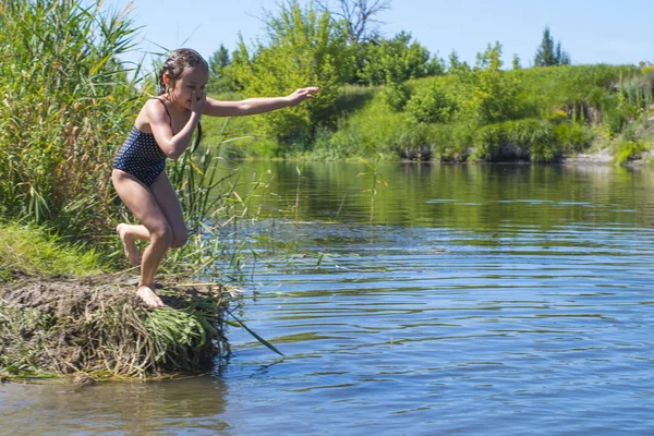 Meisje loopt door het water met een plons. in haar handen doek. — Stockfoto