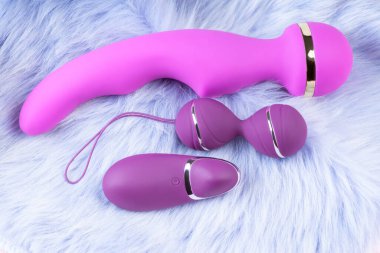 Double vaginal balls and dildo vibrator.Sex toy for adult .Pink vaginal balls and dildo on aviolet background with remote control. Strengthening the intimate muscles of the vagina.Womans health.