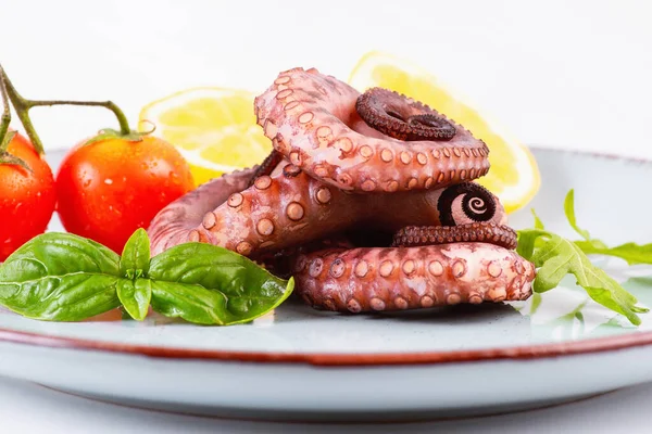 Sea food.Raw octopus tentacles in a blue plate with slices of lemon salad and small tomatoes.Close up of raw octopus.