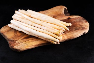 Organik Beyaz Kuşkonmaz. Beyaz organik kuşkonmaz. Mutfak tahtasında siyah arka planda..