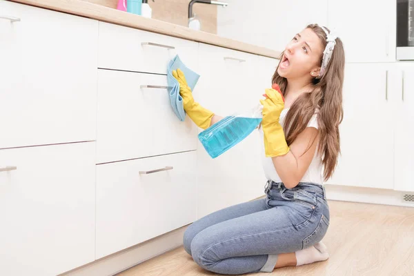 Young girl cleans the apartment. Tired girl after cleaning sits on the floor with a vacuum cleaner and speaks on the phone.