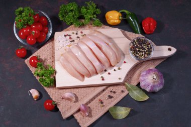 Baharatlı çiğ tavuk bifteği ve acı kırmızı biber, domates, sarımsak. Siyah arka planda çiğ organik tavuk göğsü. Üst manzara. Tavuk parçaları..