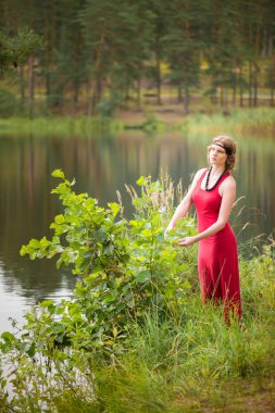 Yaz ortası sırasında lake yakınındaki ormanda genç kadın: Ligo Letonya