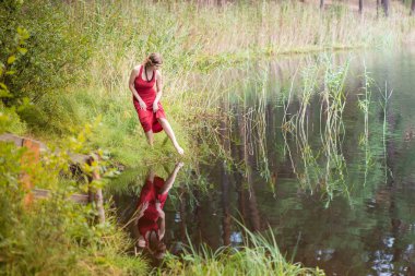 Yaz ortası sırasında lake yakınındaki ormanda genç kadın: Ligo Letonya