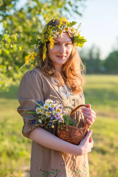 Letonya 'da yaz ortası: Ligo kutlamaları - genç bir kadın çelenk dokuyor ve çiçek topluyor