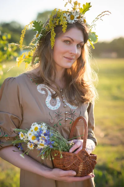 Letonya 'da yaz ortası: Ligo kutlamaları - genç bir kadın çelenk dokuyor ve çiçek topluyor