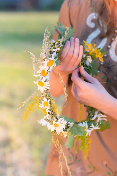 Letonya 'da yaz ortası: Ligo kutlamaları - genç bir kadın çelenk dokuyor ve çiçek topluyor