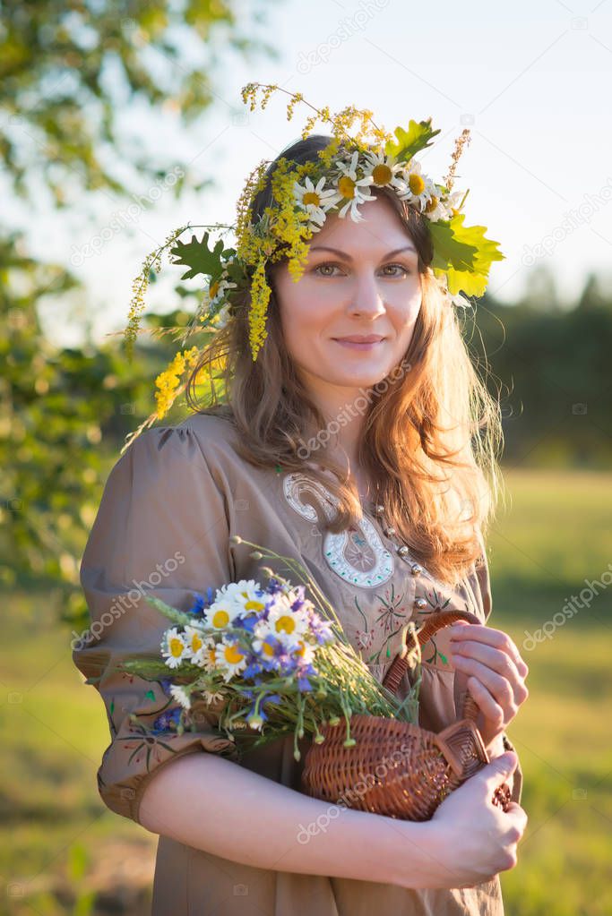 Midsummer in Latvia: celebration of Ligo - a young woman weave a wreath and collect field flowers