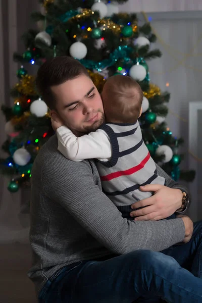 Happy father with baby boy before Christmas among decorations and gifts